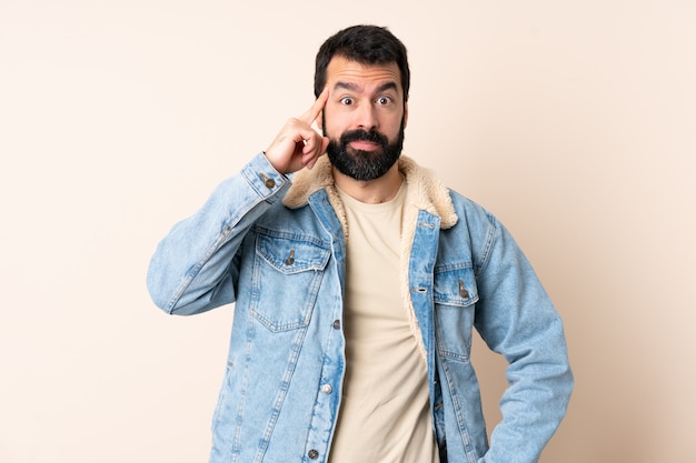 Homem caucasiano com barba sobre espaço isolado, pensando uma idéia