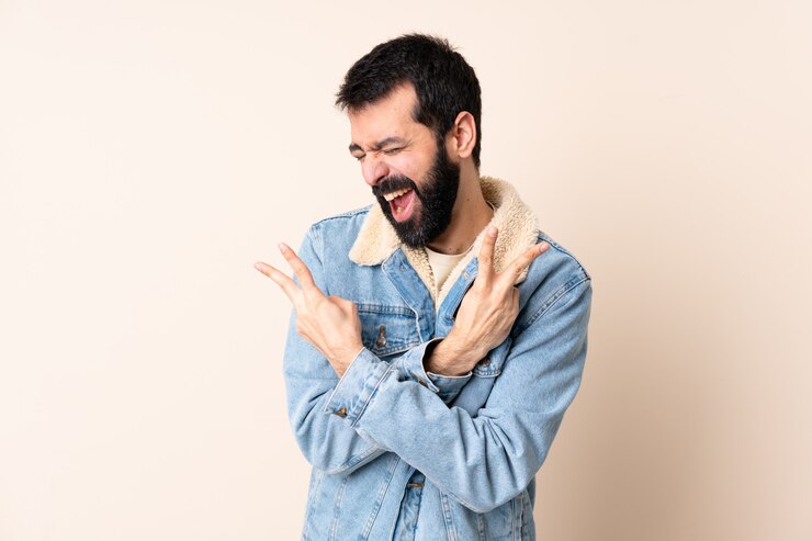 Foto homem caucasiano com barba sobre parede sorrindo e mostrando sinal de vitória