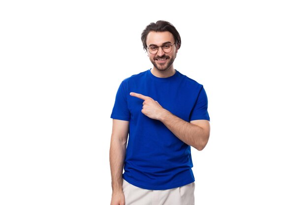 Foto homem caucasiano com cabelo escuro e bem arrumado e barba em uma camiseta azul aponta a mão para o lado