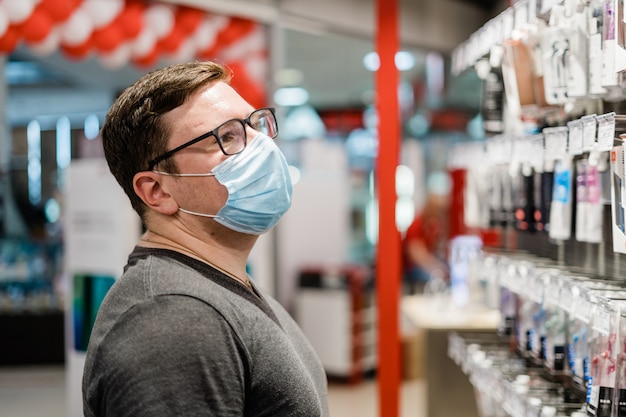 Homem caucasiano, comprar roupas com máscara médica. Novo conceito normal.