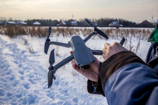Homem caucasiano de 30 anos voando no campo drone in snowy no inverno.