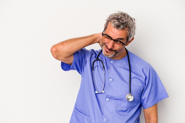 Homem caucasiano de enfermeira de meia-idade, isolado no fundo branco, tocando a parte de trás da cabeça, pensando e fazendo uma escolha.