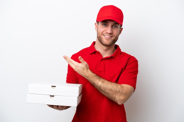 Homem caucasiano de entrega de pizza com uniforme de trabalho pegando caixas de pizza isoladas no fundo branco, estendendo as mãos para o lado para convidar para vir