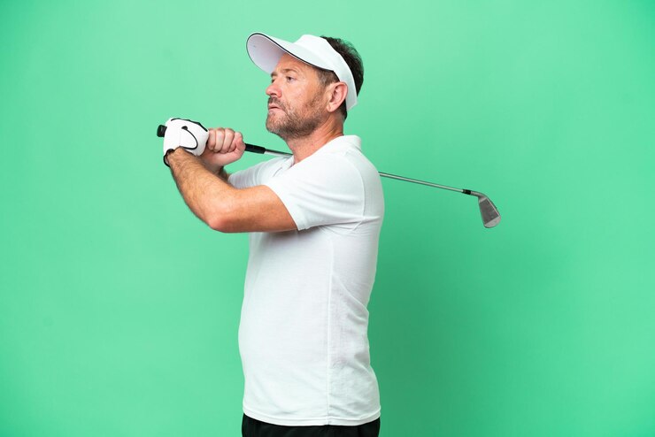 Foto homem caucasiano de meia-idade isolado em fundo verde jogando golfe