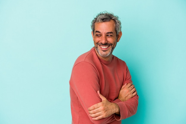 Foto homem caucasiano de meia-idade isolado em um fundo azul, rindo e se divertindo.