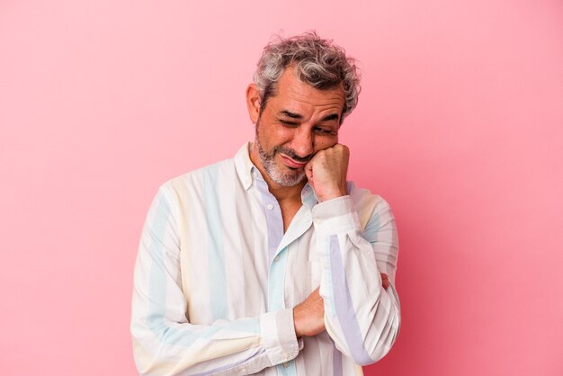 Homem caucasiano de meia-idade isolado em um fundo rosa que se sente triste e pensativo, olhando para o espaço da cópia.