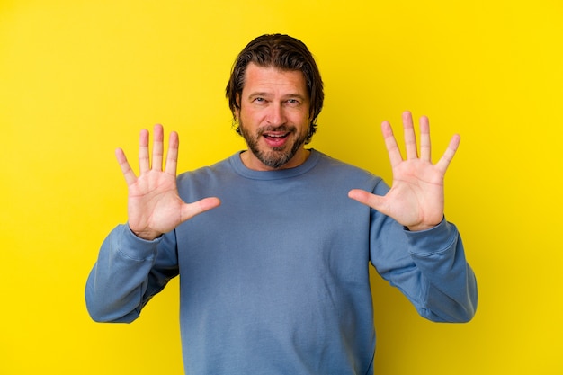 Homem caucasiano de meia-idade isolado na parede amarela, rejeitando alguém mostrando um gesto de nojo.