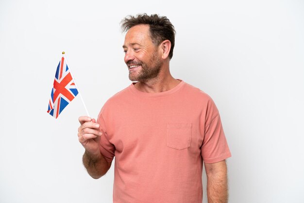 Foto homem caucasiano de meia-idade segurando a bandeira inglesa isolada no fundo branco olhando de lado