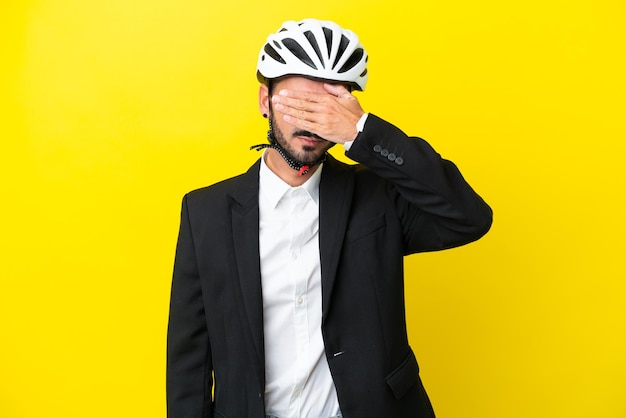 Homem caucasiano de negócios com um capacete de bicicleta isolado em fundo amarelo cobrindo os olhos pelas mãos Não quer ver algo