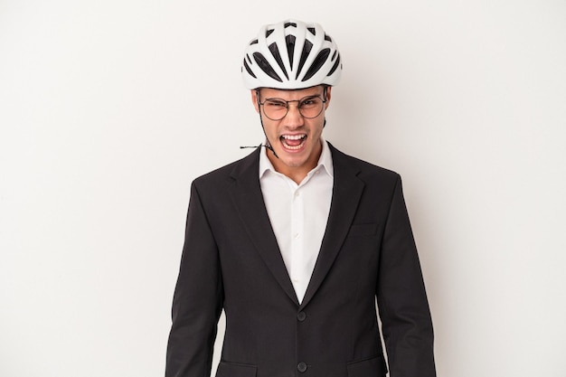 Homem caucasiano de negócios jovem segurando o capacete de bicicleta isolado no fundo branco, gritando muito irritado e agressivo.