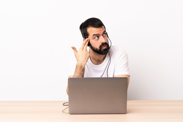 Homem caucasiano de telemarketing trabalhando com um fone de ouvido e com laptop com problemas para fazer o gesto de suicídio.