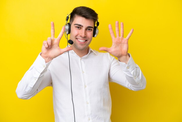 Homem caucasiano de telemarketing trabalhando com um fone de ouvido isolado em fundo amarelo contando oito com os dedos