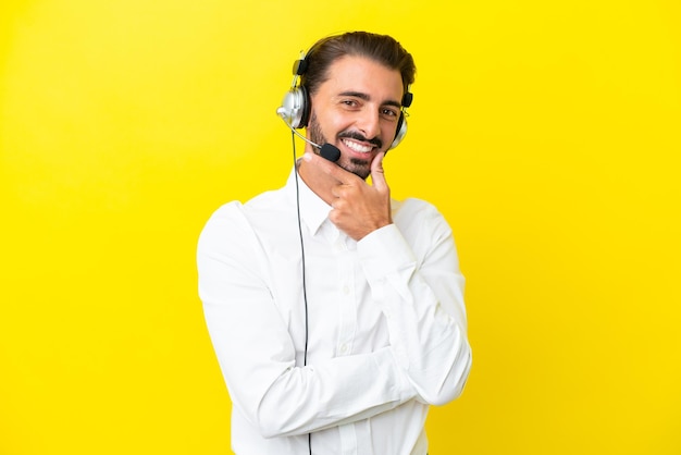 Homem caucasiano de telemarketing trabalhando com um fone de ouvido isolado em fundo amarelo sorrindo