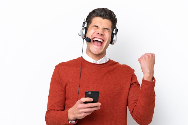 Homem caucasiano de telemarketing trabalhando com um fone de ouvido isolado no fundo branco com telefone em posição de vitória