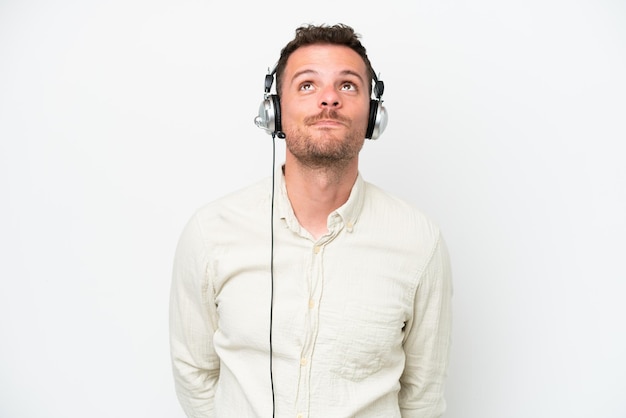 Homem caucasiano de telemarketing trabalhando com um fone de ouvido isolado no fundo branco e olhando para cima