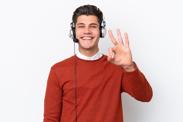 Homem caucasiano de telemarketing trabalhando com um fone de ouvido isolado no fundo branco feliz e contando três com os dedos