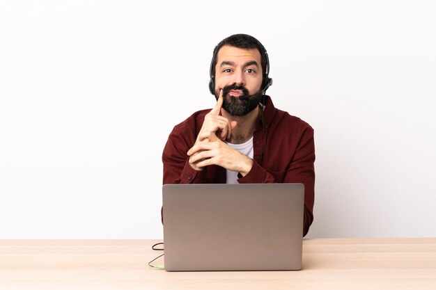Homem caucasiano do operador de telemarketing trabalhando com um fone de ouvido e com o laptop e pensando.