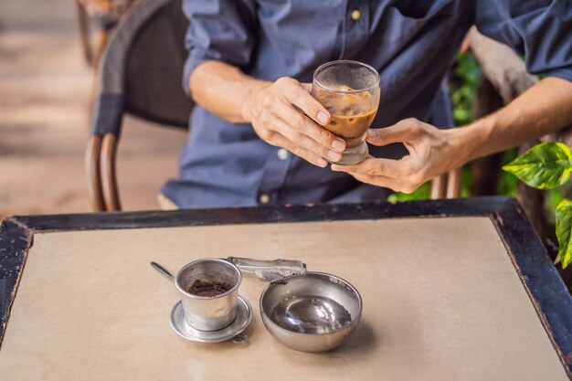 Homem caucasiano e café vietnamita tradicional por gotejamento a partir de um filtro fino