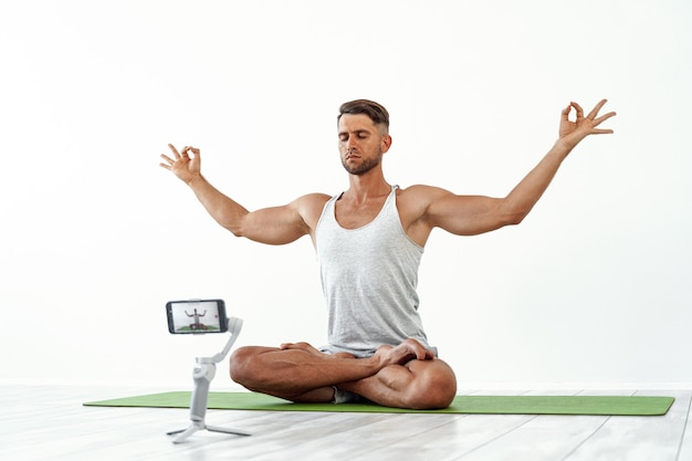 Foto homem caucasiano em forma registrando um blog ou fazendo streaming de exercícios de ioga