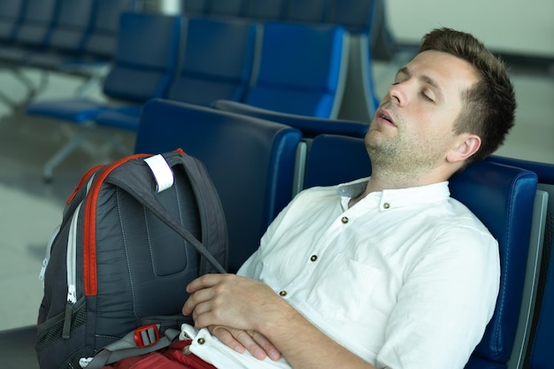 Homem caucasiano está dormindo na sala de estar no aeroporto