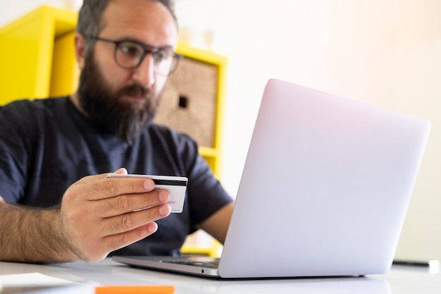 homem caucasiano fazendo compras online no escritório Foco seletivo para segurar o cartão de crédito