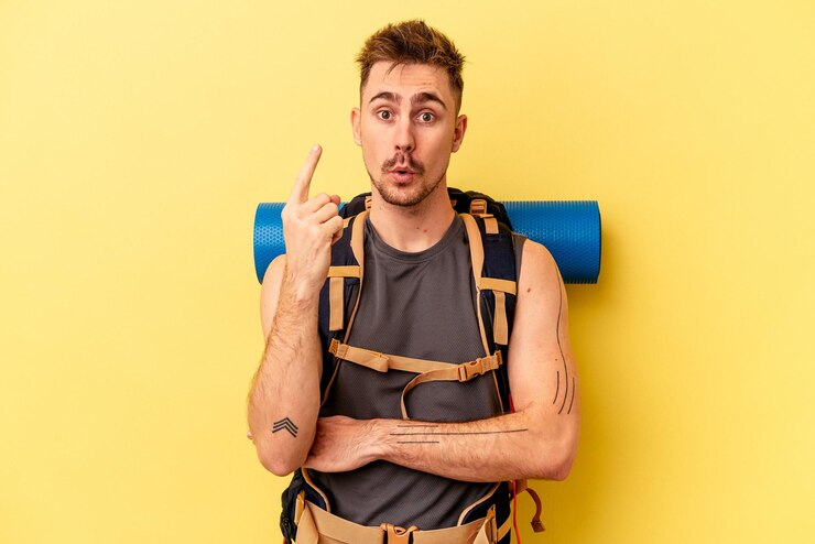 Foto homem caucasiano jovem alpinista isolado em fundo amarelo, tendo uma ótima ideia, conceito de criatividade.