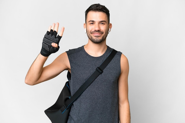 Homem caucasiano jovem esporte com bolsa esportiva sobre fundo branco isolado feliz e contando quatro com os dedos