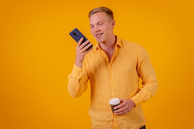 Homem caucasiano loiro em um fundo amarelo sorrindo chamando amigos