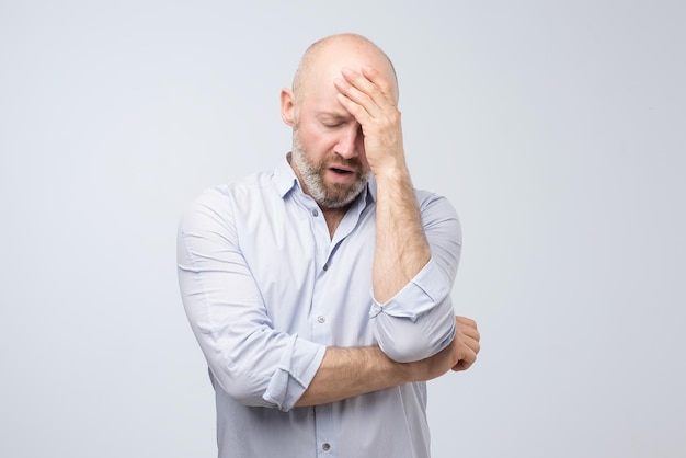 Homem caucasiano maduro com dor de cabeça, sentindo-se cansado após um dia difícil