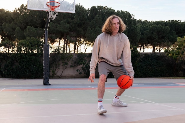 Homem caucasiano quicando a bola entre as pernas na quadra de basquete em um conceito de parque urbano de esporte urbano no espaço de cópia de rua para texto