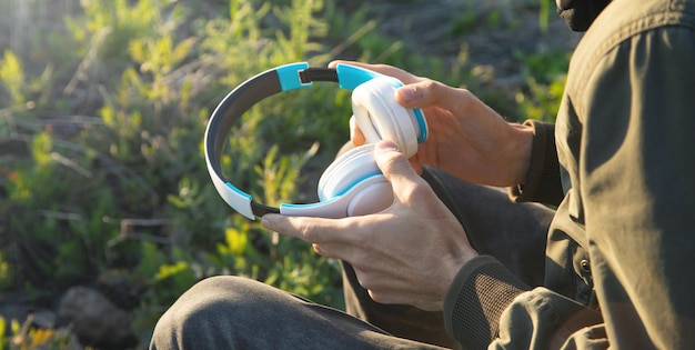 Homem caucasiano segurando fones de ouvido ao ar livre