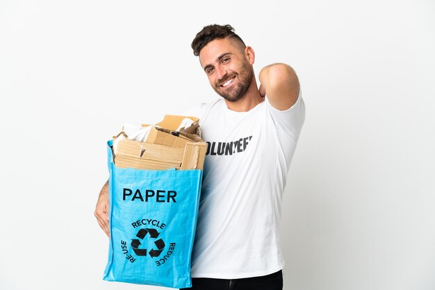 Homem caucasiano segurando uma sacola cheia de papel para reciclar isolado no fundo branco rindo