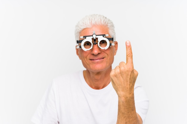 Homem caucasiano sênior, vestindo um quadro de julgamento optometrista mostrando o número um com o dedo.