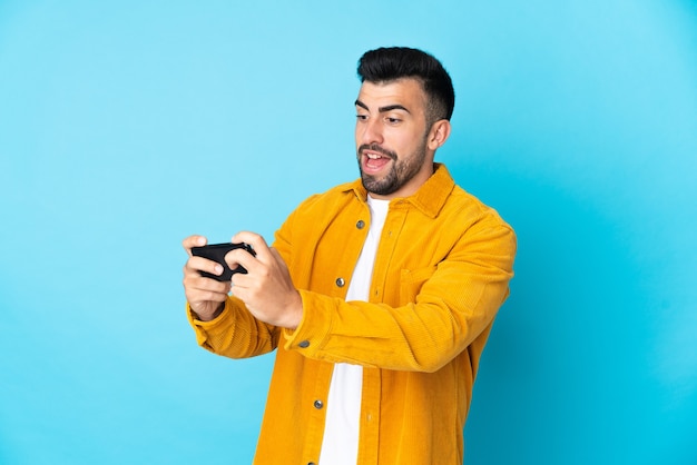 Homem caucasiano sobre fundo azul isolado brincando com o celular