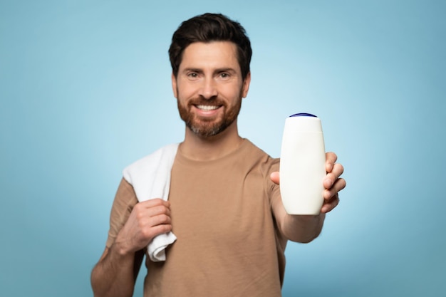 Homem caucasiano sorridente de meia-idade mostrando frasco de xampu vazio com maquete para publicidade de design