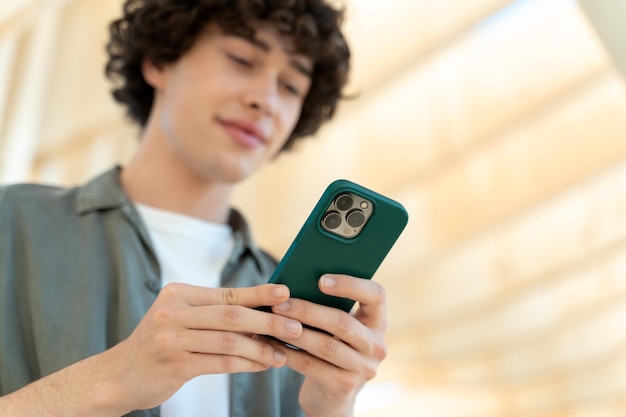 Homem caucasiano sorrindo feliz usando smartphone na cidade