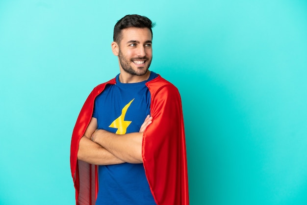 Foto homem caucasiano super-herói isolado em um fundo azul com os braços cruzados e feliz