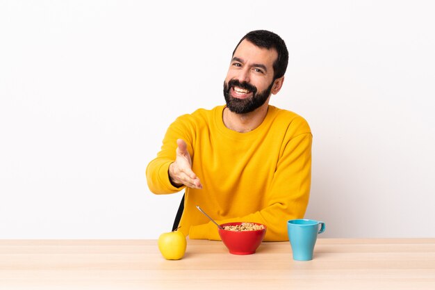 Homem caucasiano, tomando café da manhã em uma mesa, apertando as mãos para fechar um bom negócio