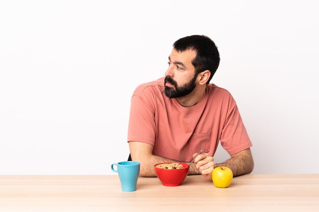 Homem caucasiano tomando café da manhã em uma mesa de braços cruzados