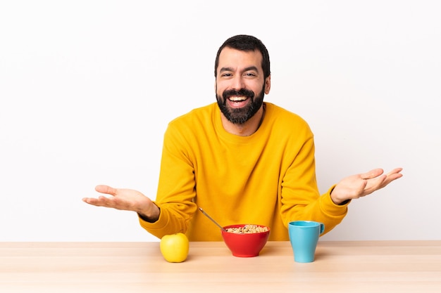 Homem caucasiano tomando café da manhã em uma mesa feliz e sorridente.