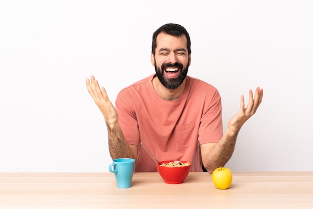 Homem caucasiano tomando café da manhã em uma mesa sorrindo