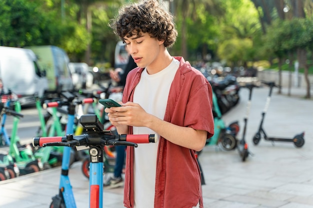 Homem caucasiano usando smartphone para desbloquear patinete urbano