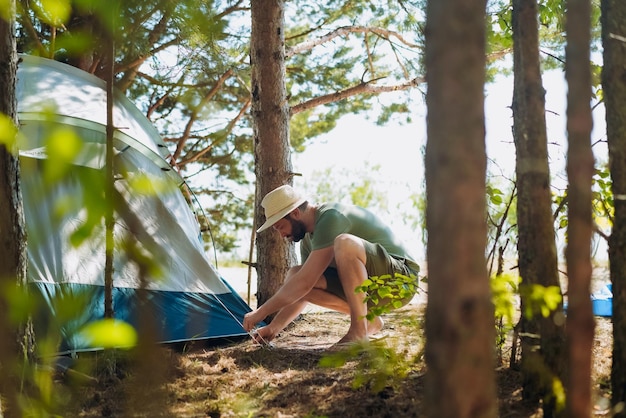 Homem caucasiano usando um chapéu colocando uma barraca Conceito de acampamento familiar