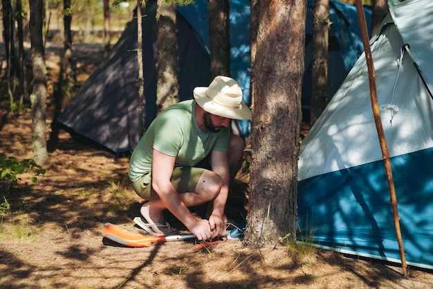 homem caucasiano usando um chapéu montando uma barraca Conceito de acampamento familiar