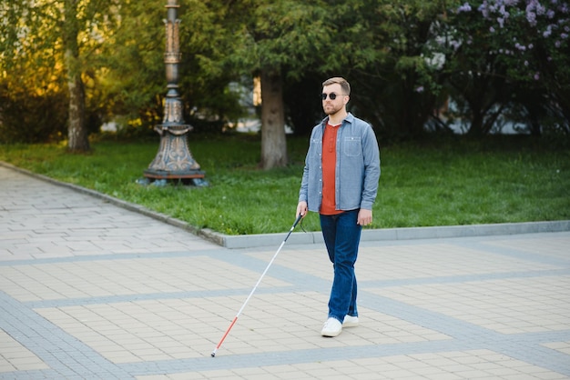 Homem cego andando na calçada segurando a bengala