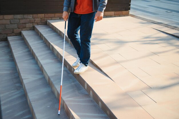 Homem cego andando na calçada segurando a bengala