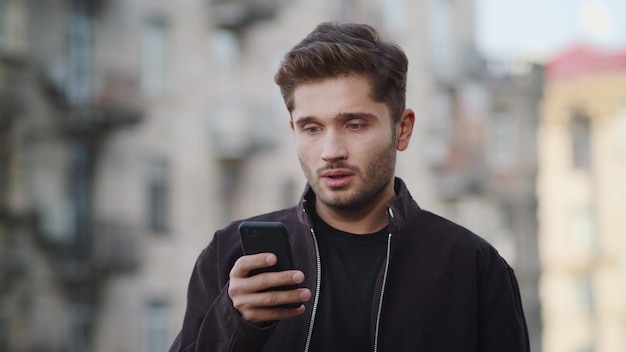 Homem chateado usando telefone fora Cara desapontado recebendo mensagem ao ar livre