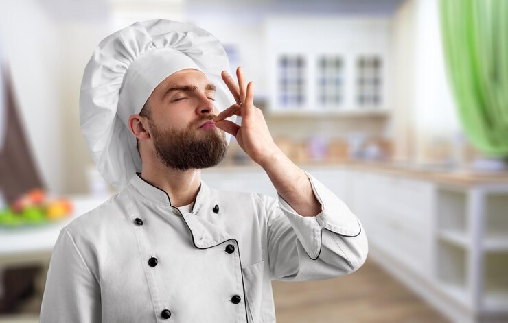 Foto homem chef profissional mostrando sinal de delicioso. chef masculino de uniforme branco com sinal perfeito.