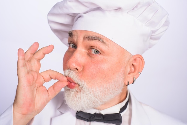 Homem chef profissional mostrando sinal de um delicioso chef masculino de uniforme branco com cozinheiro de sinal perfeito
