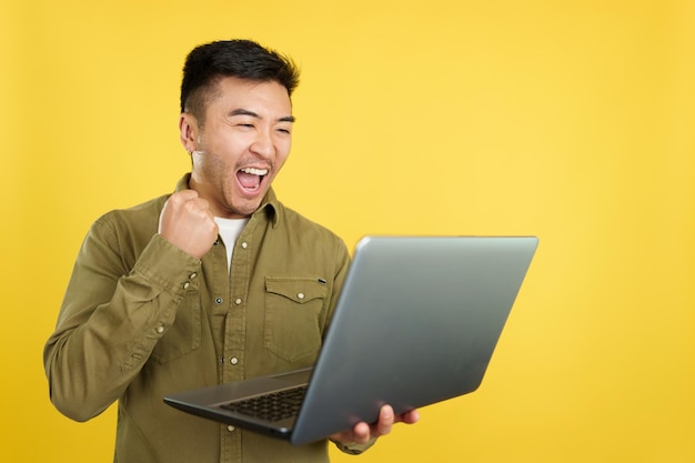 Homem chinês comemorando enquanto olha para o laptop